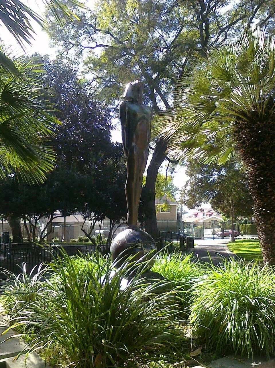 A statue in a park surrounded by trees and plants