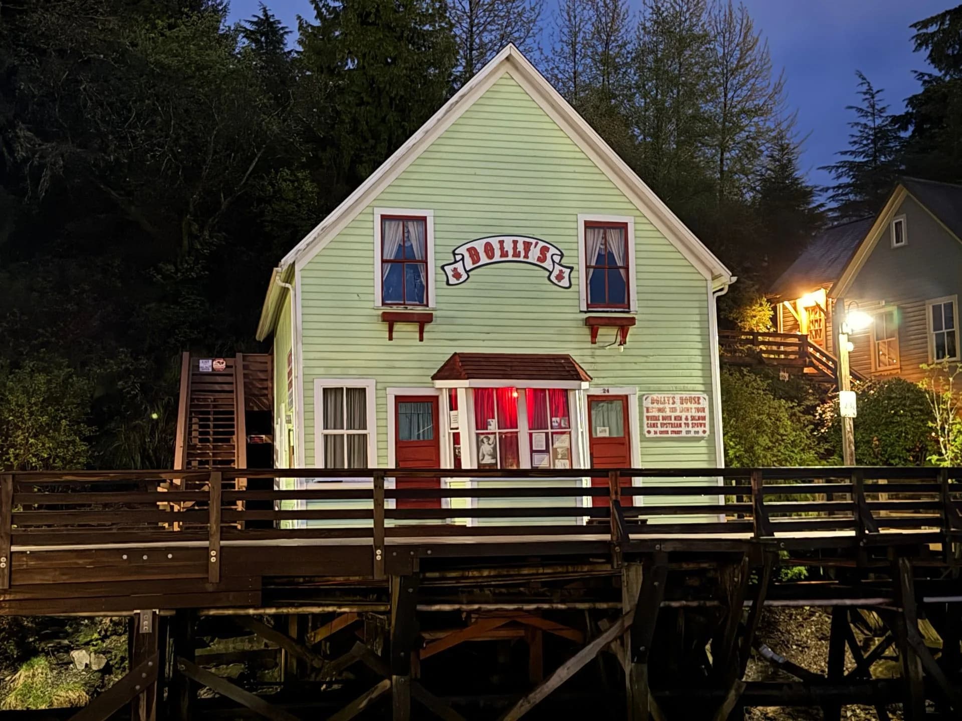 Green and white historic building on a wooden bridge at dusk