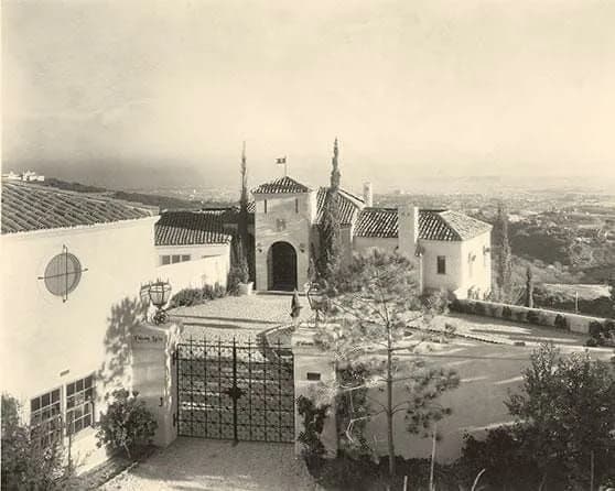 A black and white photo of a house on a hill