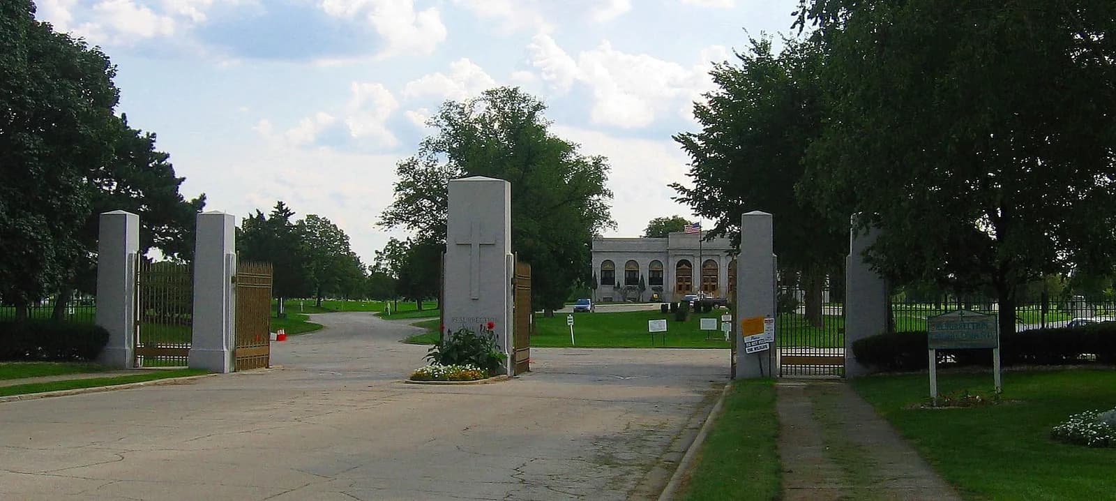 The entrance to a cemetery with a large building in the background