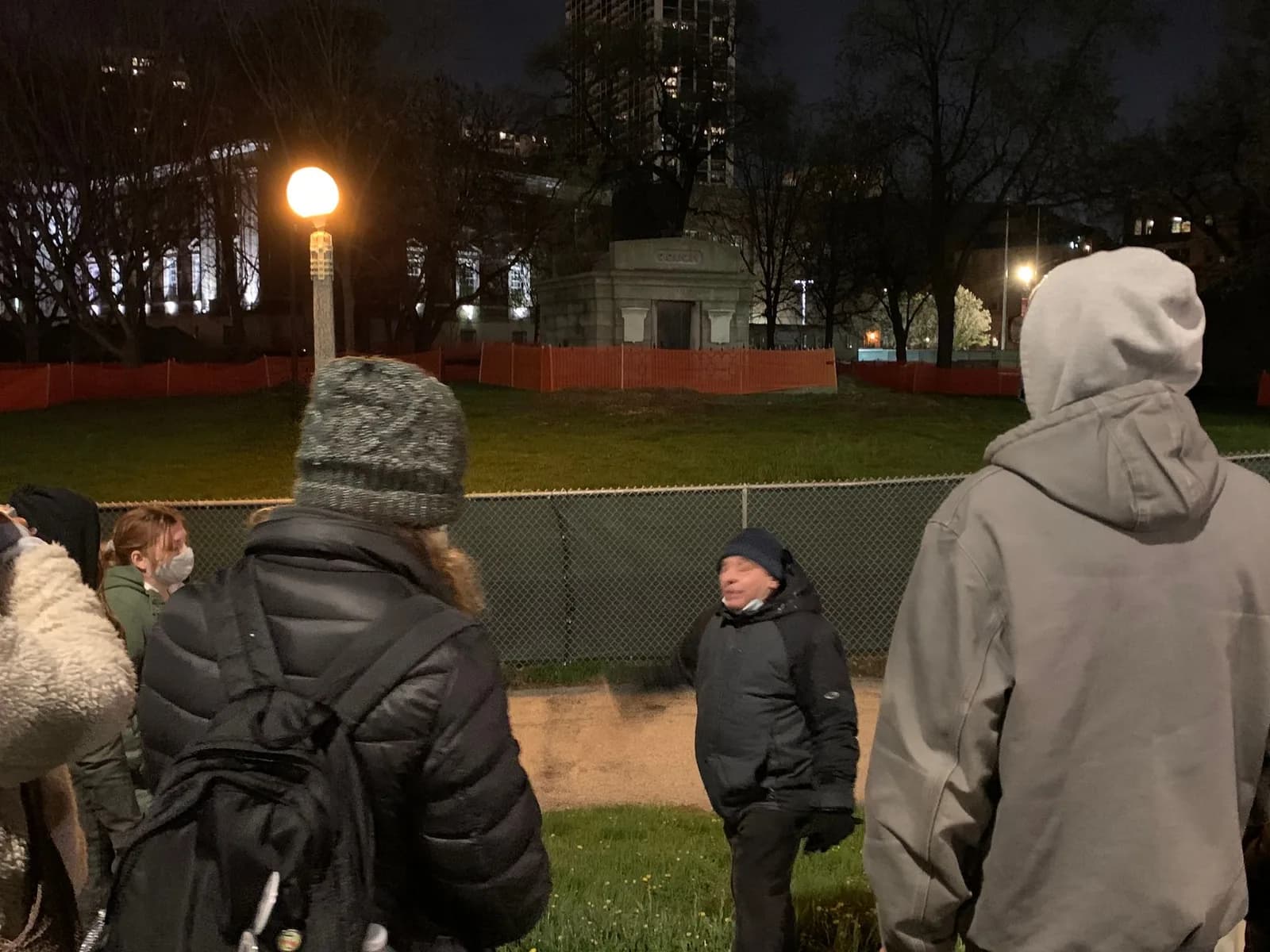 A group of people are standing in a park at night