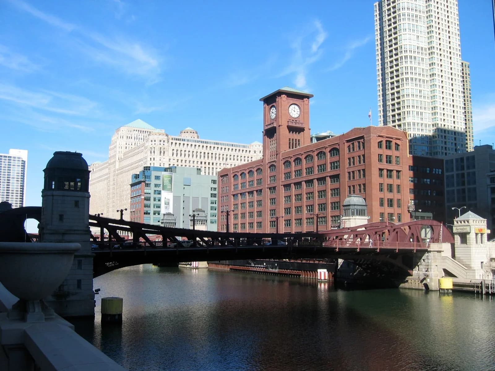 A bridge over a river with a clock tower in the background