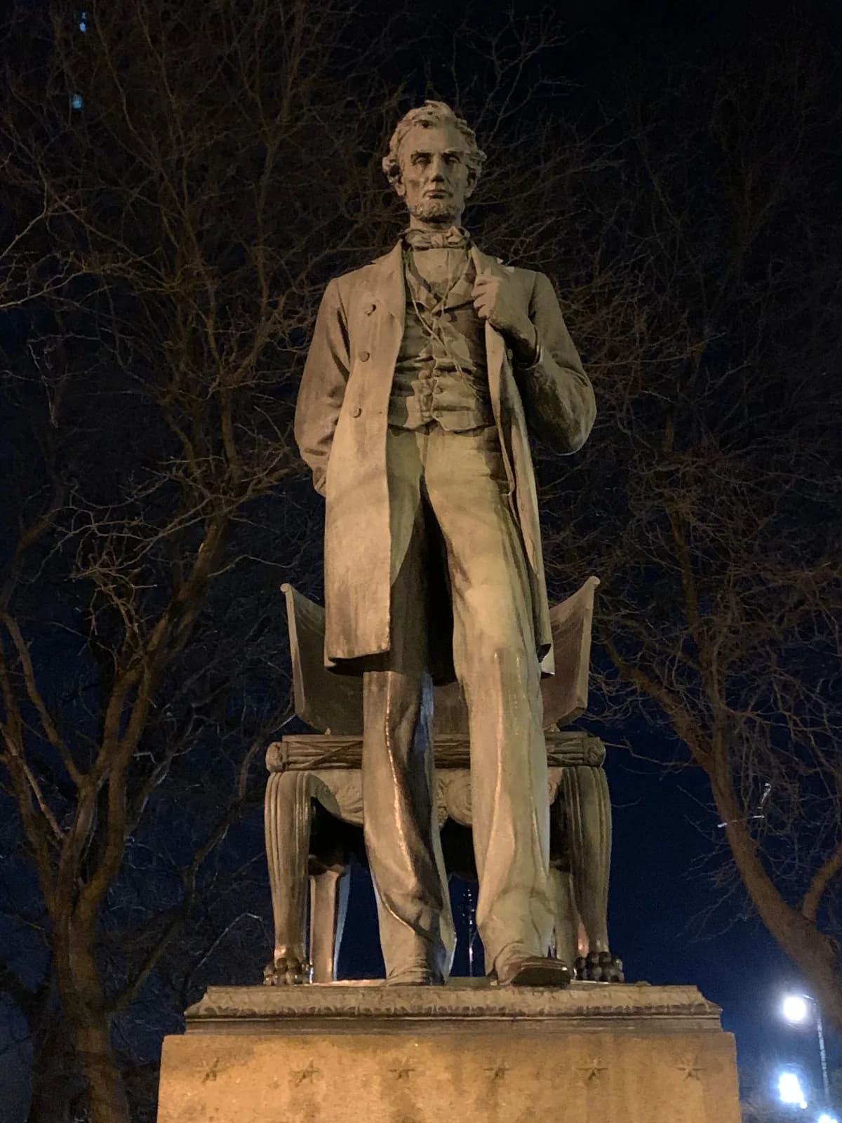 A statue of abraham lincoln is lit up at night