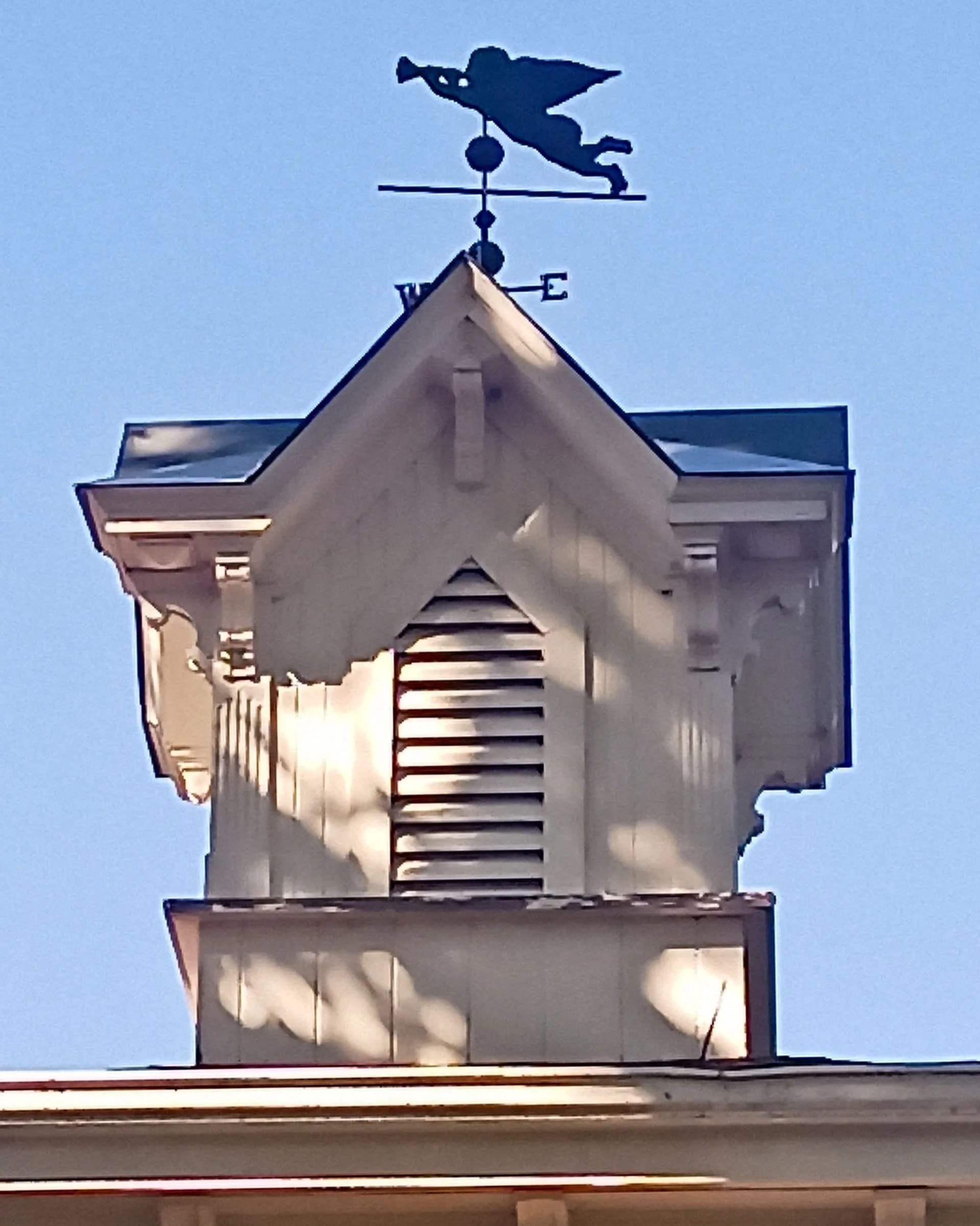 A weather vane on top of a building with the letter e on it