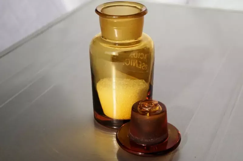 A glass bottle filled with a yellow substance is sitting on a table.