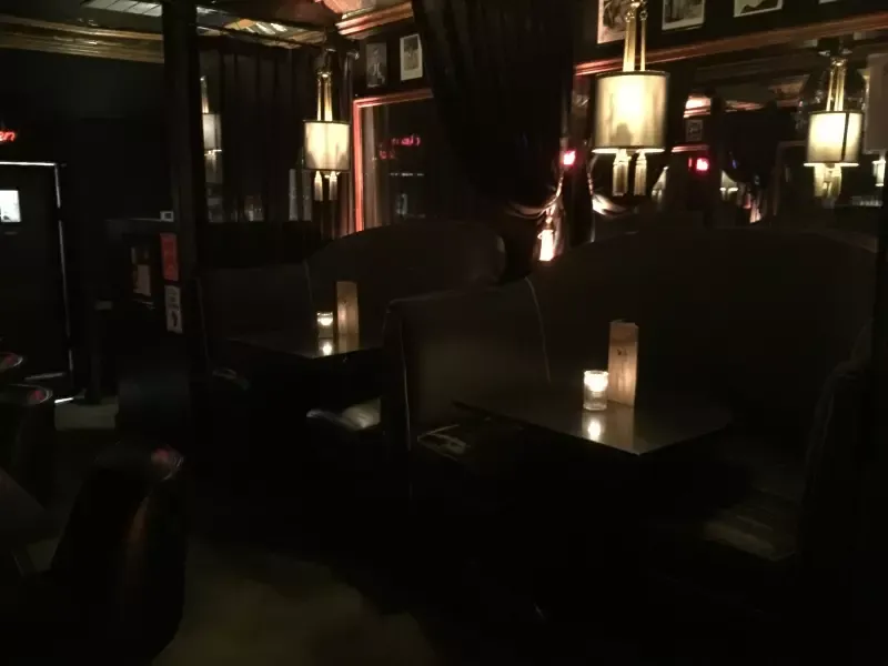 A dark room with tables and chairs and lamps