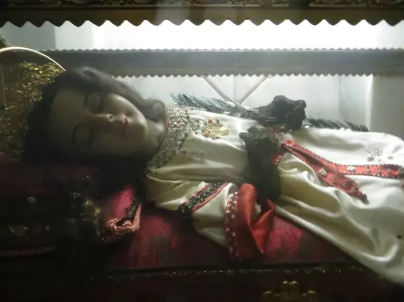 A woman is laying in a coffin with her eyes closed