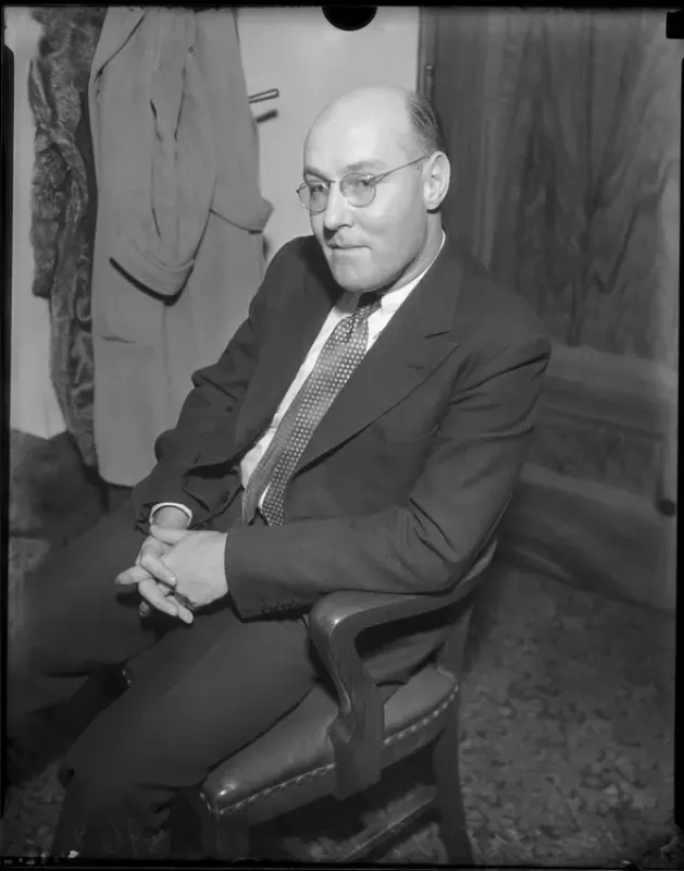 A man in a suit and tie is sitting in a chair