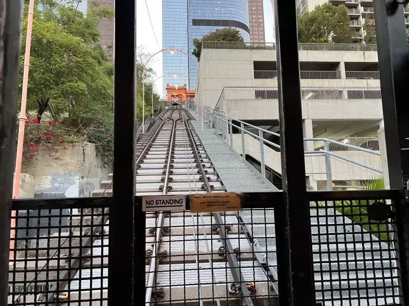 A view of a train track through a window with a building in the background.