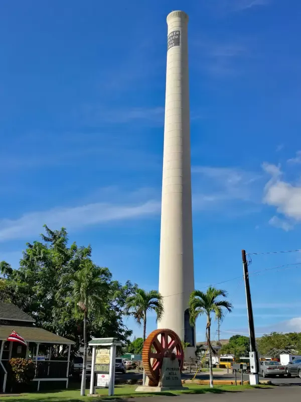 A tall white tower with a red wheel in front of it