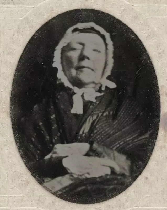 A black and white photo of a woman wearing a white hat