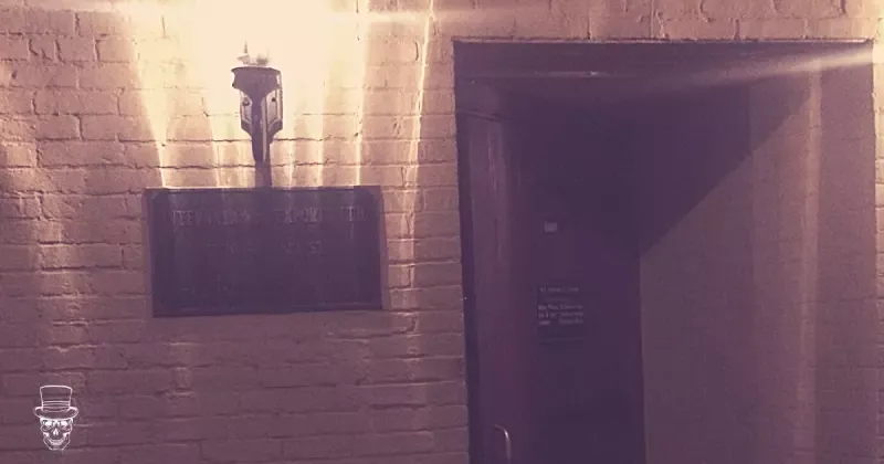 A brick wall with a door and a lamp on it.
