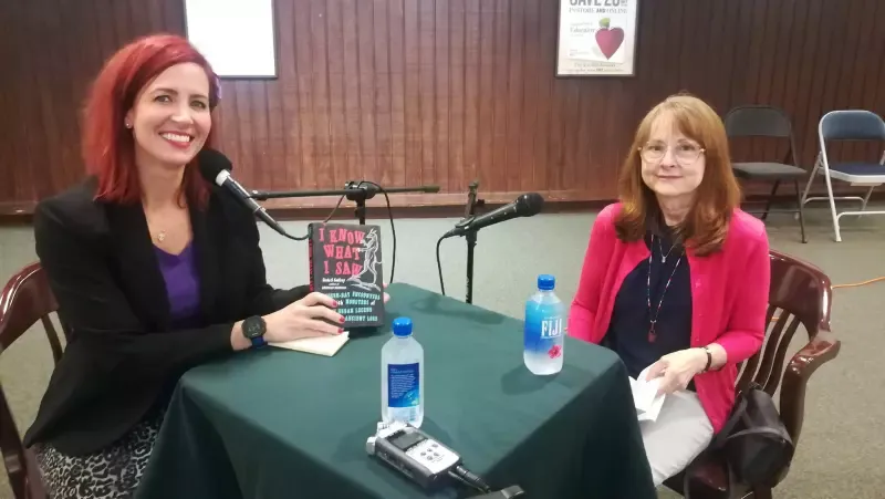 Two women are sitting at a table with a book on it