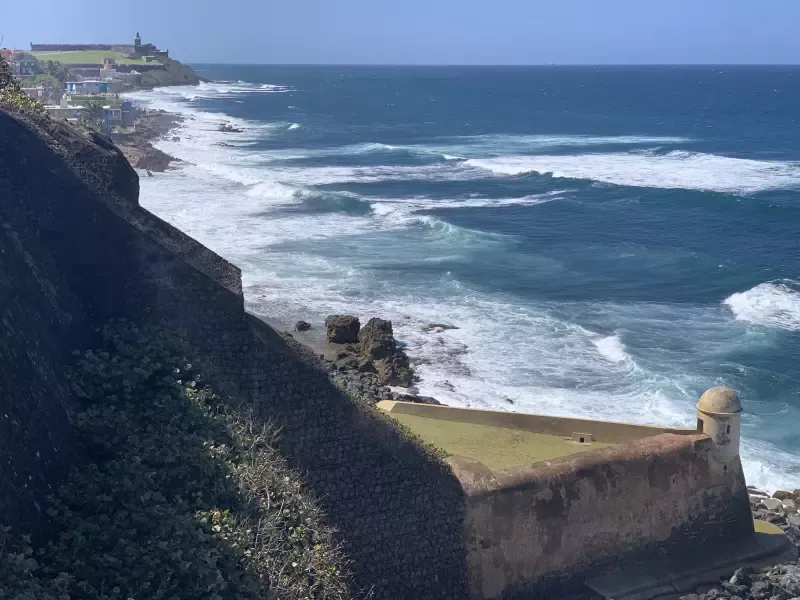 A view of a cliff overlooking the ocean with waves crashing on the shore.