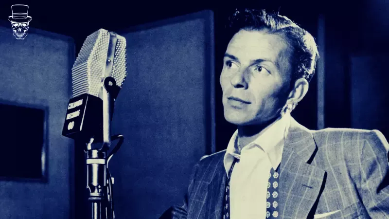 A man in a suit and tie is standing in front of a microphone.