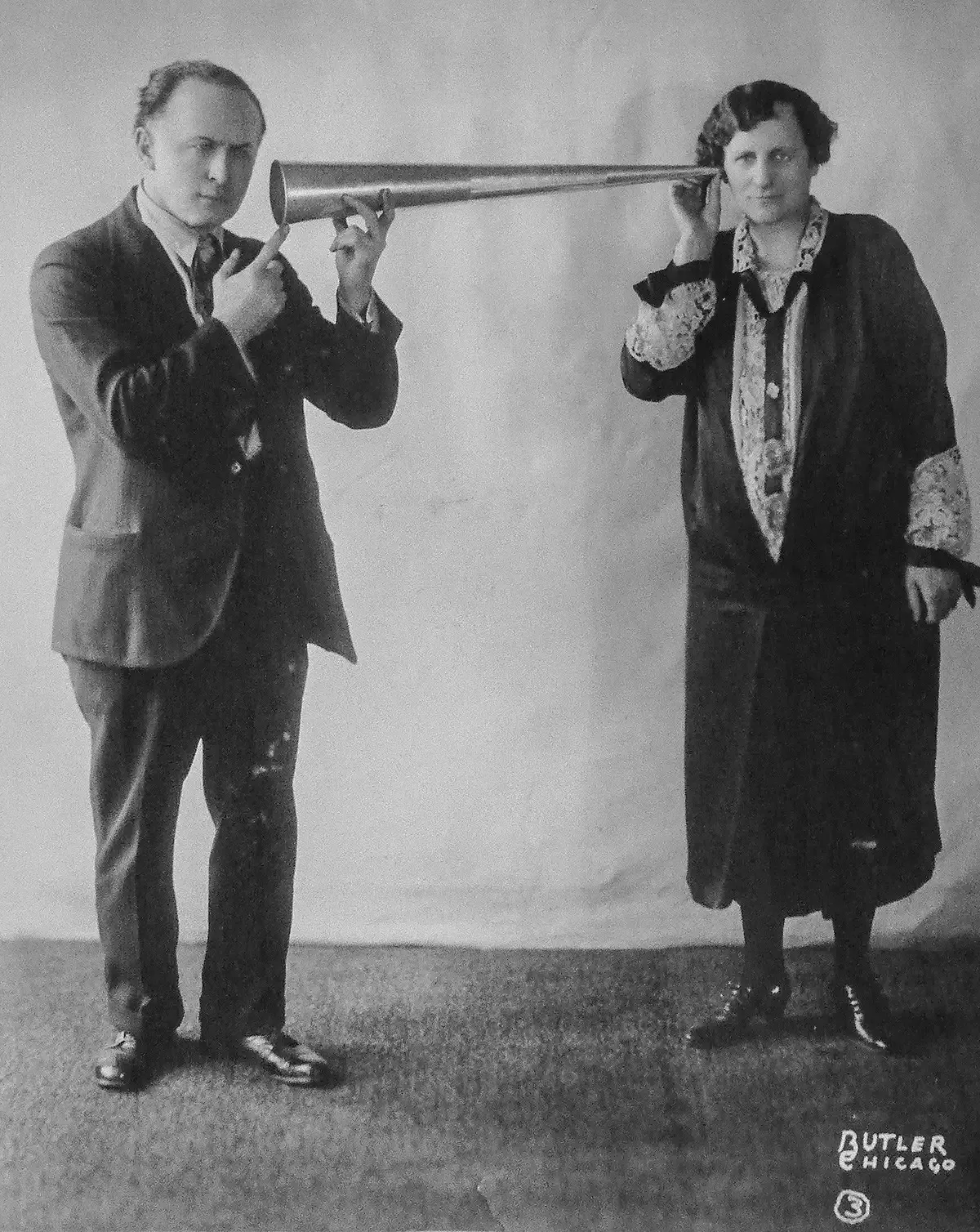 A black and white photo of a man holding a trumpet next to a woman