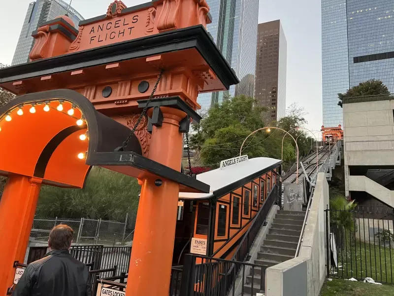 A man is standing in front of a sign that says angels flight