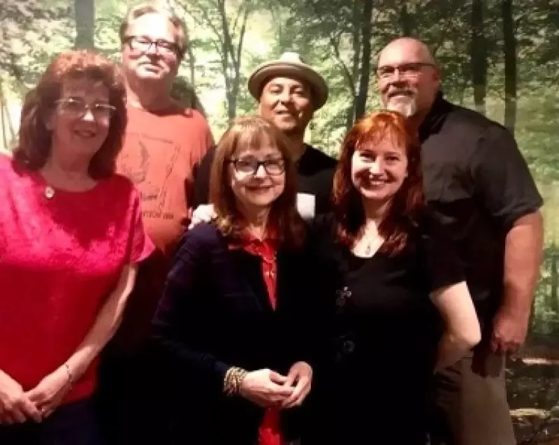 A group of people are posing for a picture in front of a forest.