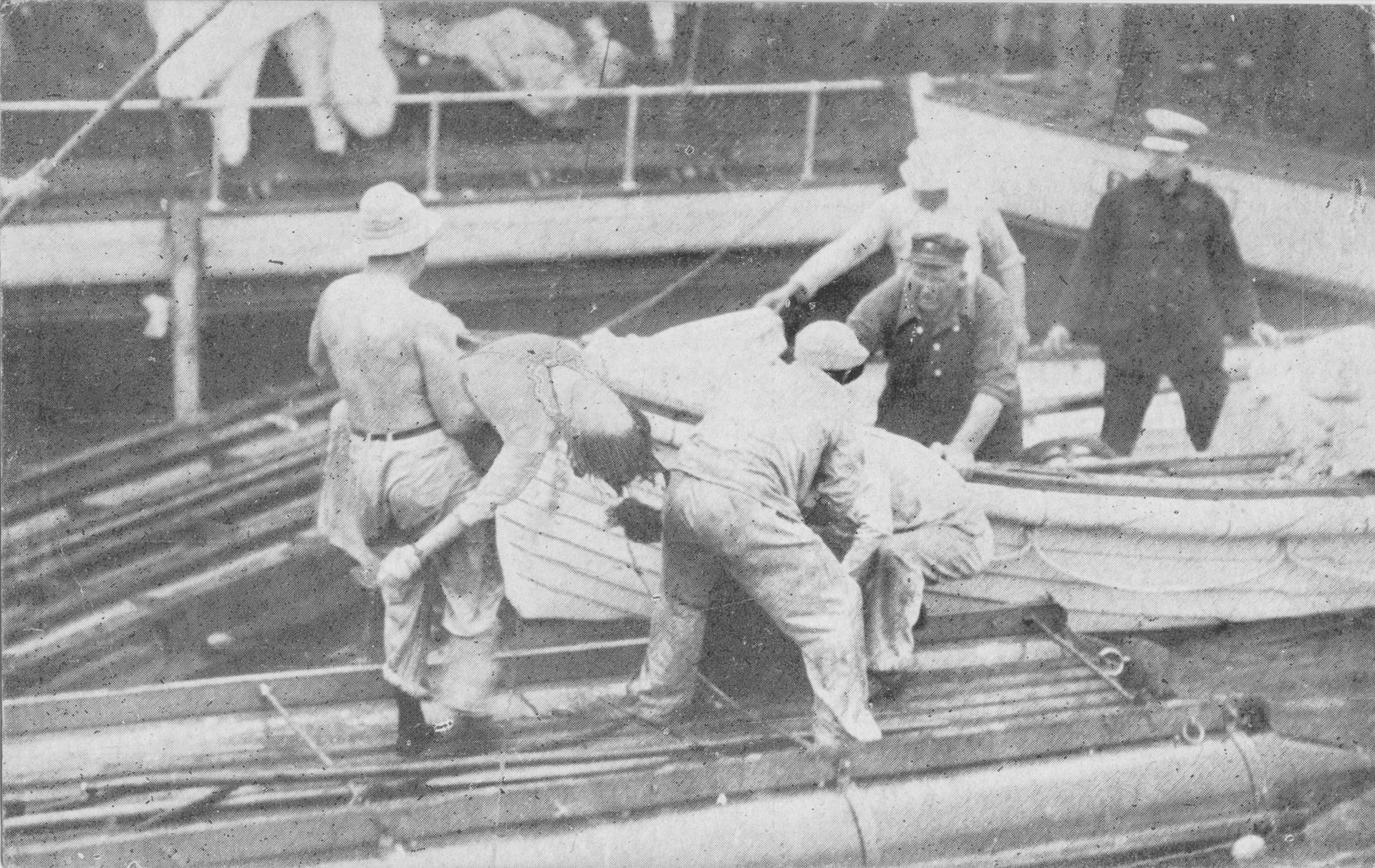 Men on a ship deck work together, possibly loading or securing cargo; black and white photo.
