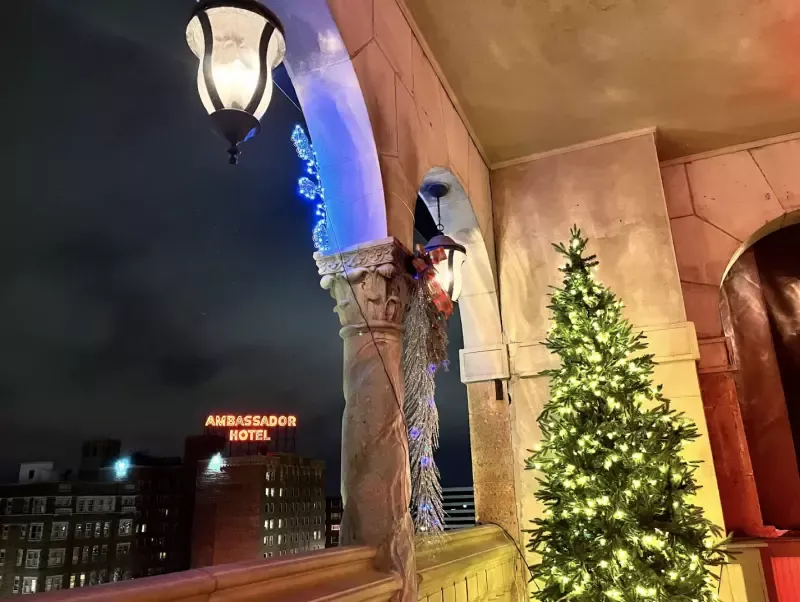 A balcony with a christmas tree and a lamp on it.