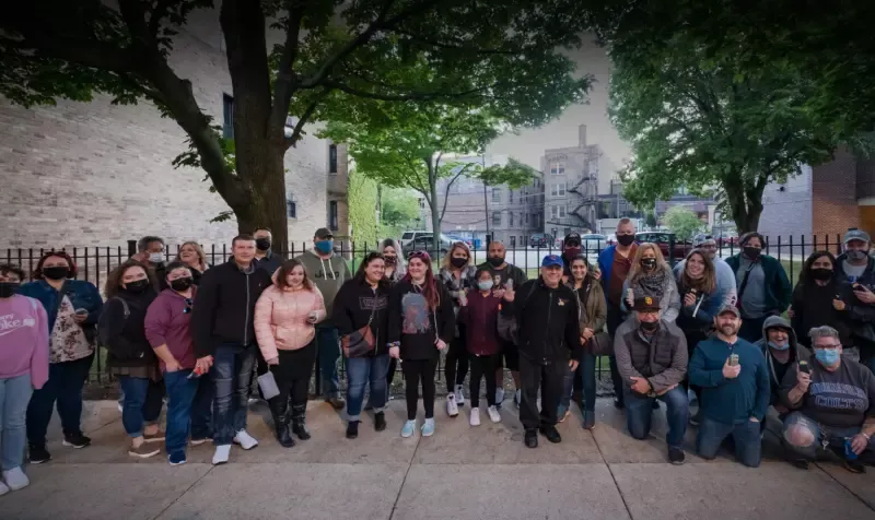 A large group of people are posing for a picture on a sidewalk.