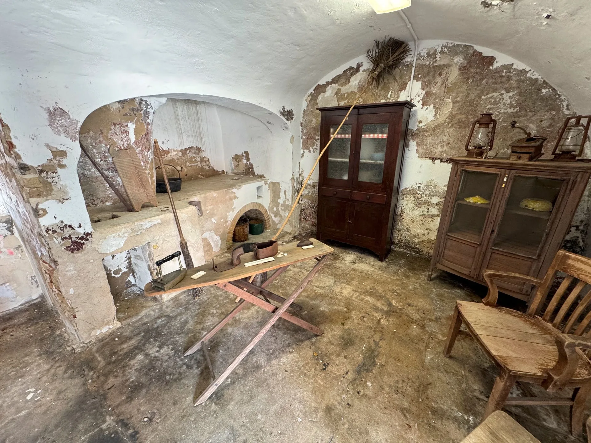 Dilapidated interior with an old oven, wooden furniture, and peeling walls.