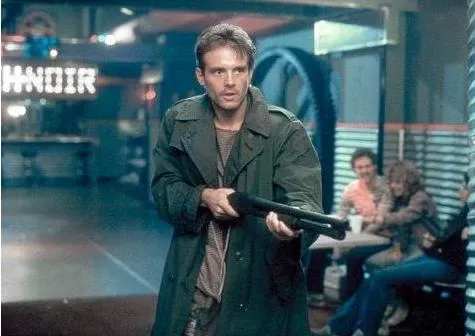 Man with shotgun, trench coat in a diner. Neon sign, couple at a table in the background.