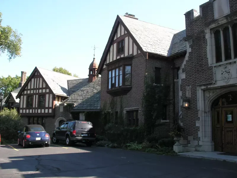Two cars are parked in front of a large brick building