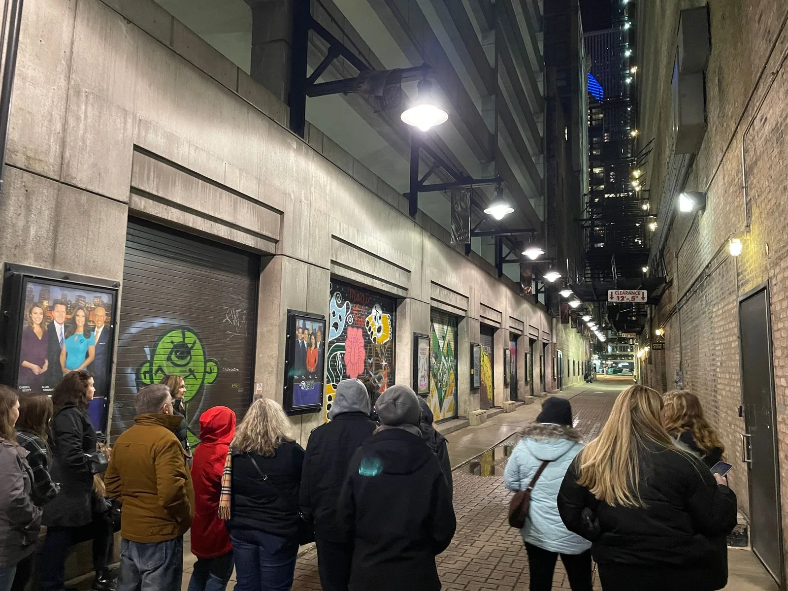A group of people are walking down a dark alleyway