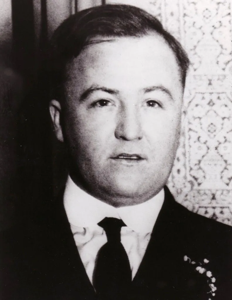 A black and white photo of a man in a suit and tie