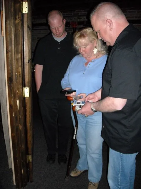Two men and a woman are looking at something in a dark room