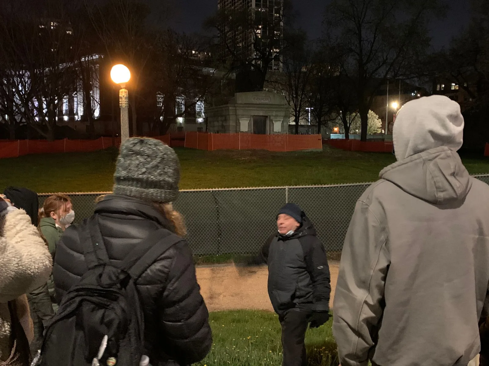 A group of people are standing in a park at night