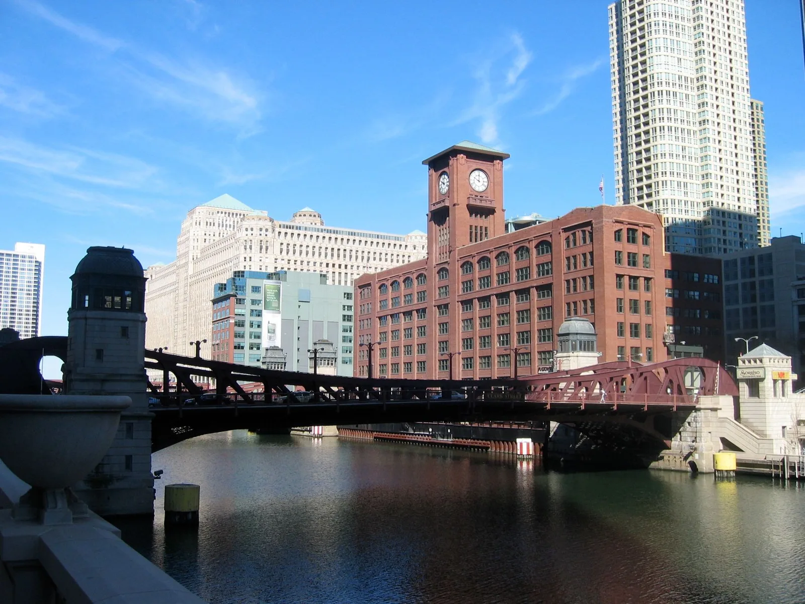 A bridge over a river with a clock tower in the background