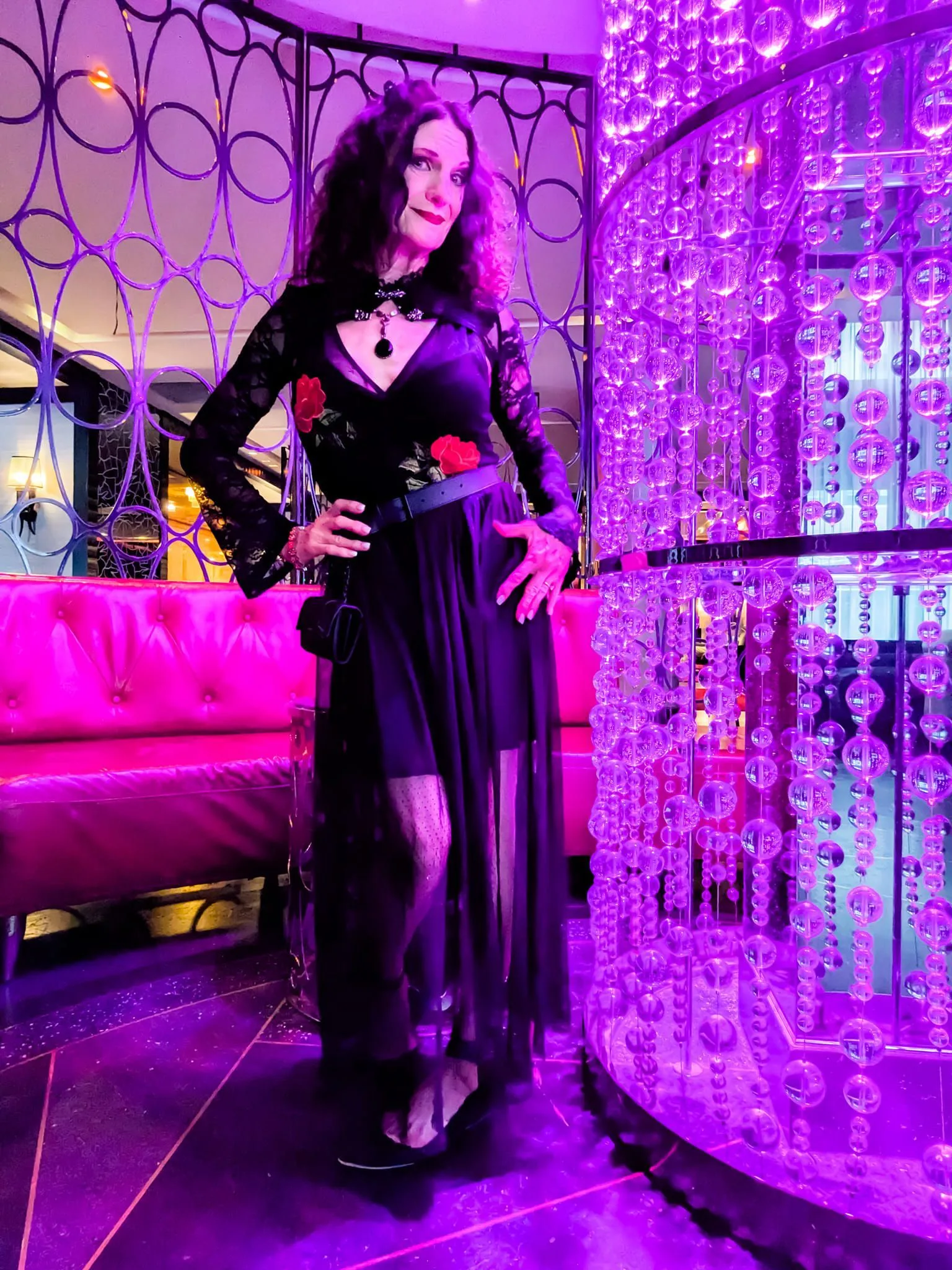 A woman in a black dress is standing in front of a purple wall