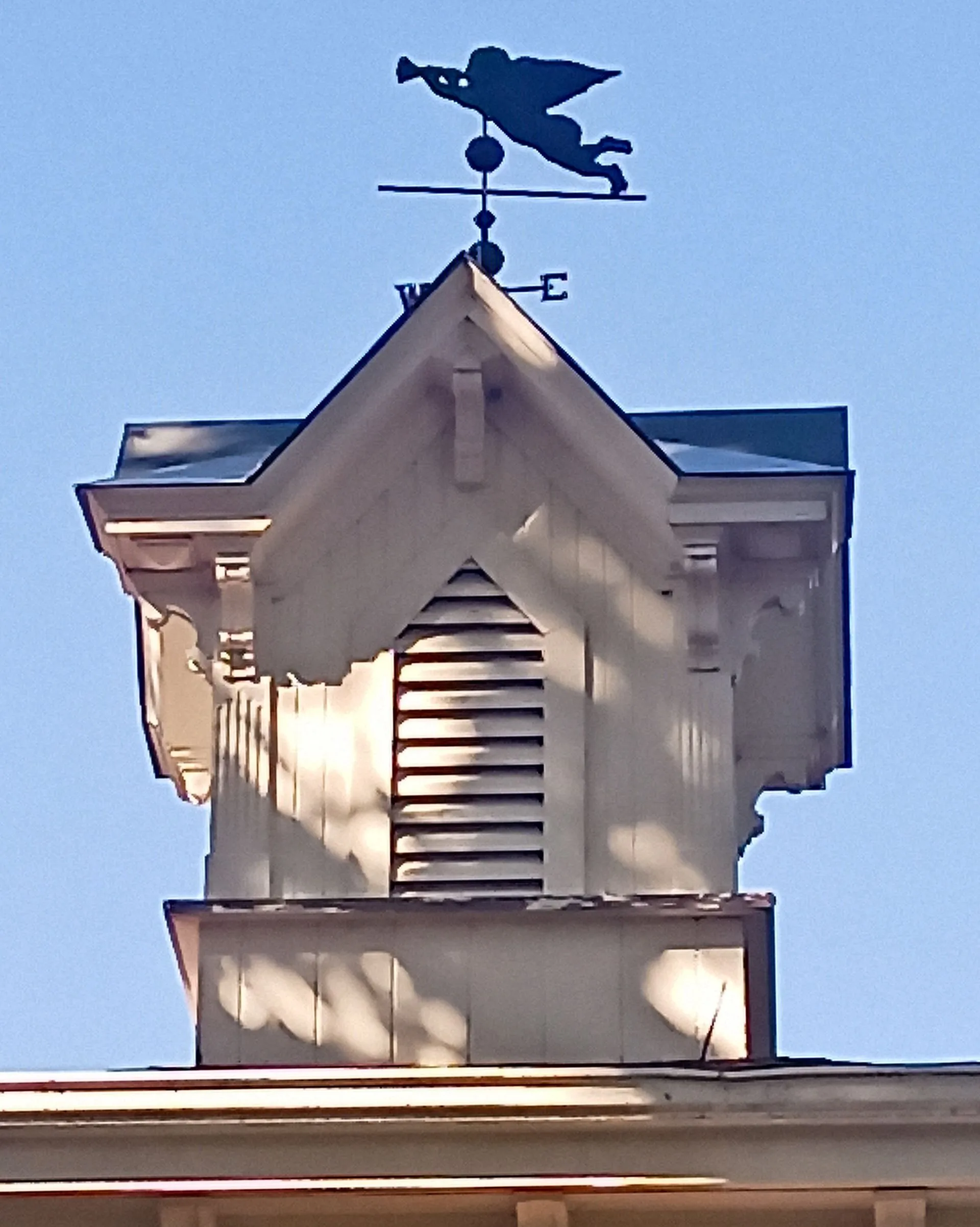 A weather vane on top of a building with the letter e on it
