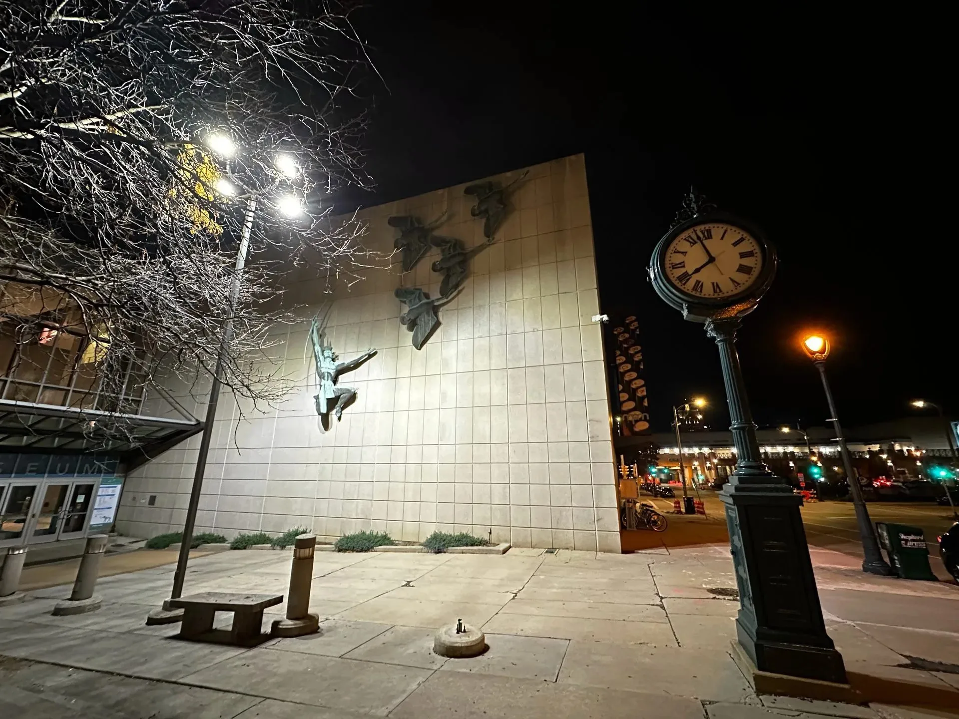 Street clock and sculpture wall outside the Milwaukee Public Museum at night